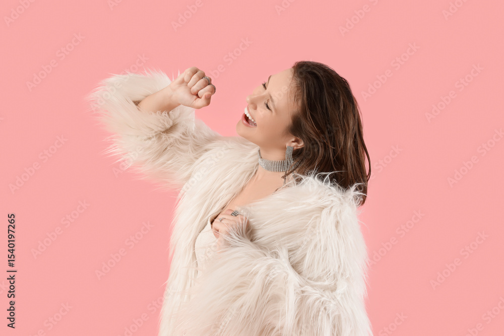 Young woman in fur coat dancing on pink background Young woman in fur coat dancing on pink background