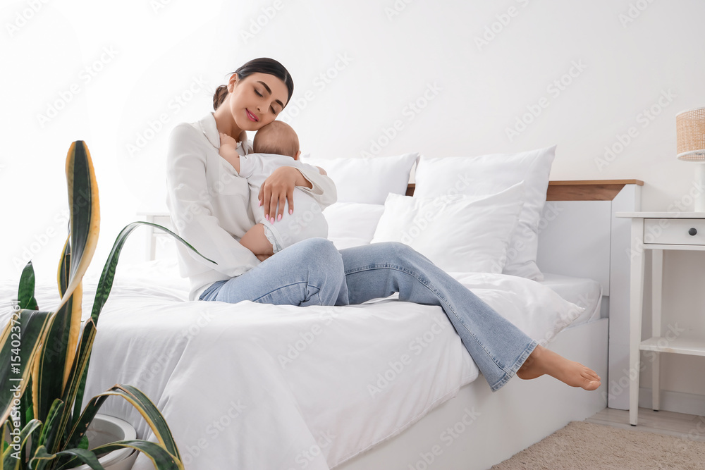 Young mother with her little baby sitting in bedroom Young mother with her little baby sitting in bedroom