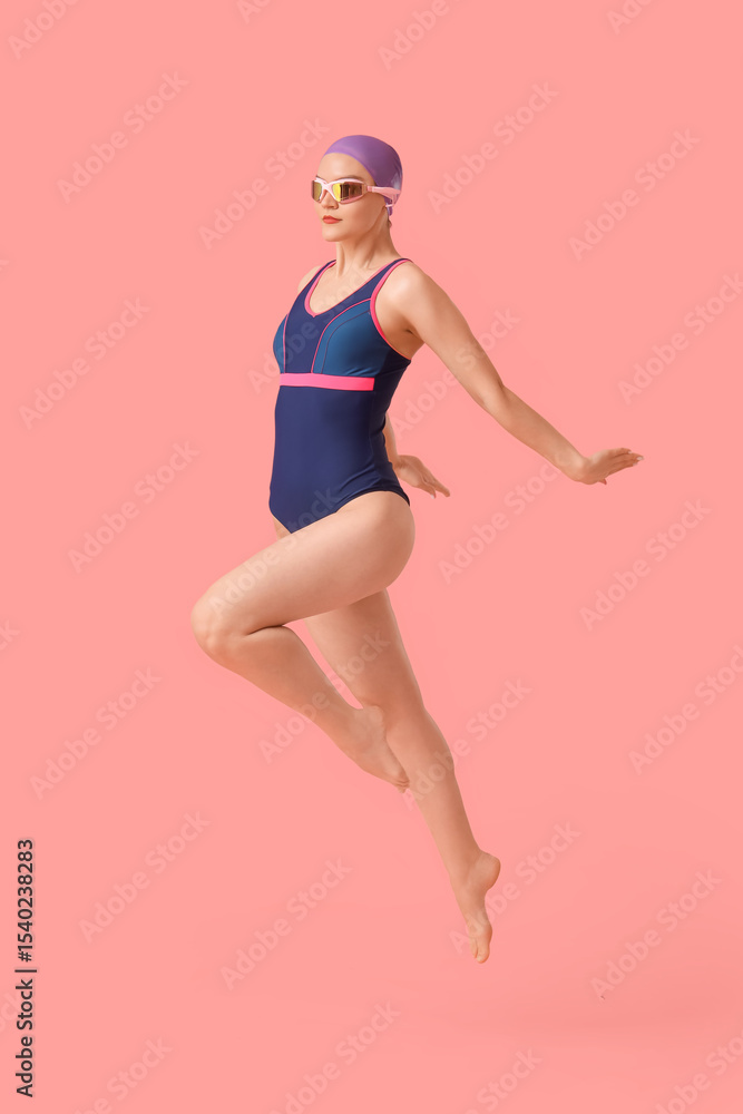 Jumping female swimmer on pink background Jumping female swimmer on pink background