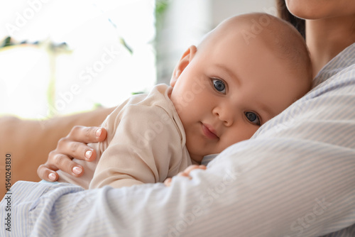 Beautiful young happy mother hugging her cute little daughter on sofa at home