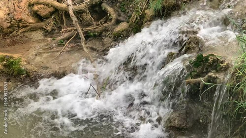 A stream of crystal-clear water flows down a rocky hillside