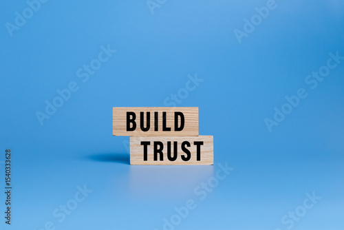 male hand putting wooden blocks with build trust words isolated on blue background