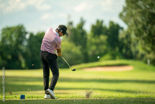 A man is swinging a golf club on a green course