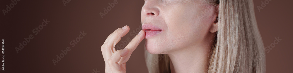 Caucasian woman gently touching her lips with her fingers. Long straight blonde hair cascading down her shoulders Caucasian woman gently touching her lips with her fingers. Long straight blonde hair cascading down her shoulders