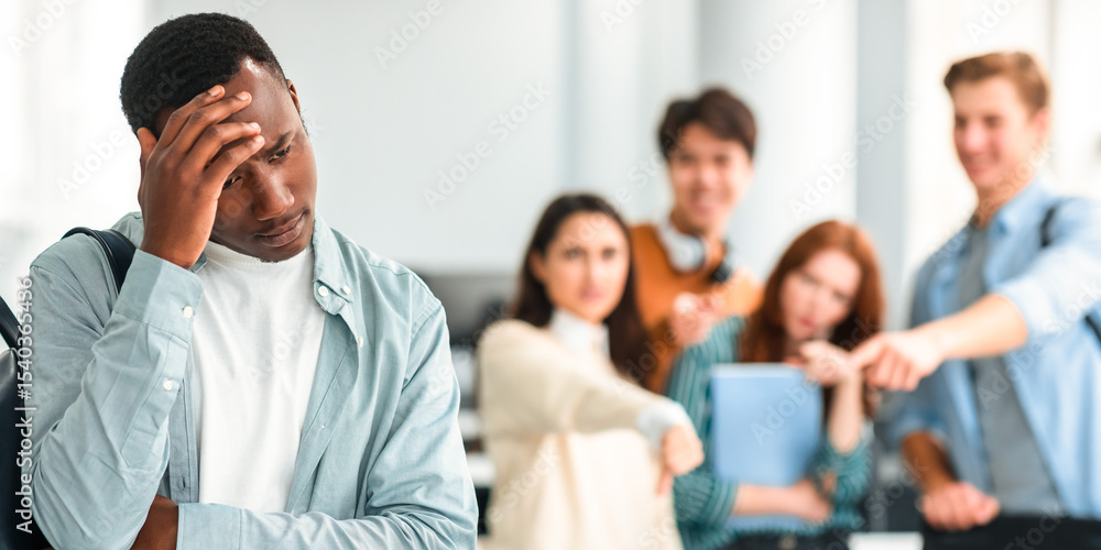 Obraz premium Bullying Concept. Rude diverse group of people mocking and making fun of sad african american guy, pointing fingers at him and laughing, standing in blurred background. Prank, abuse, public disgrace