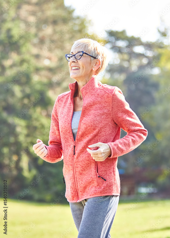 Fototapeta premium Smiling active senior woman jogging running and walking doing fitness in the park