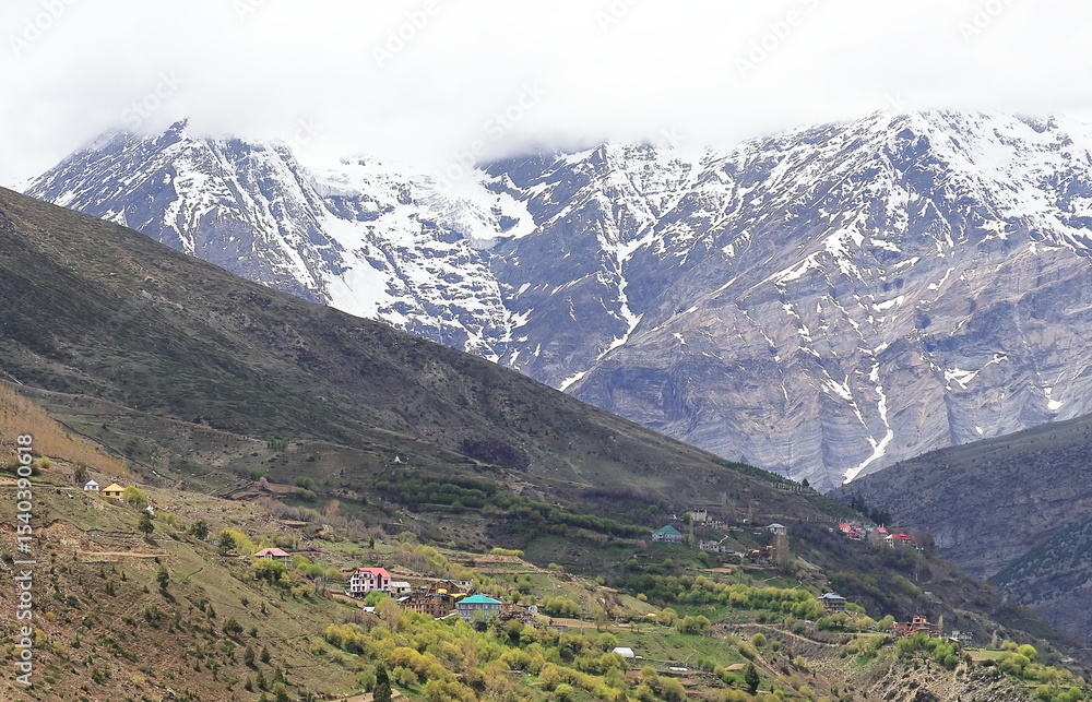 Fototapeta premium beautiful remote mountain village of lahaul valley, scenic view of snowcapped peak of himalayas, lahaul and spiti in himachal pradesh in india