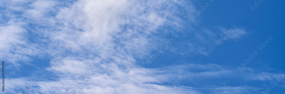 Obraz premium Clear blue sky with a few clouds. The sky is very bright and the clouds are scattered throughout