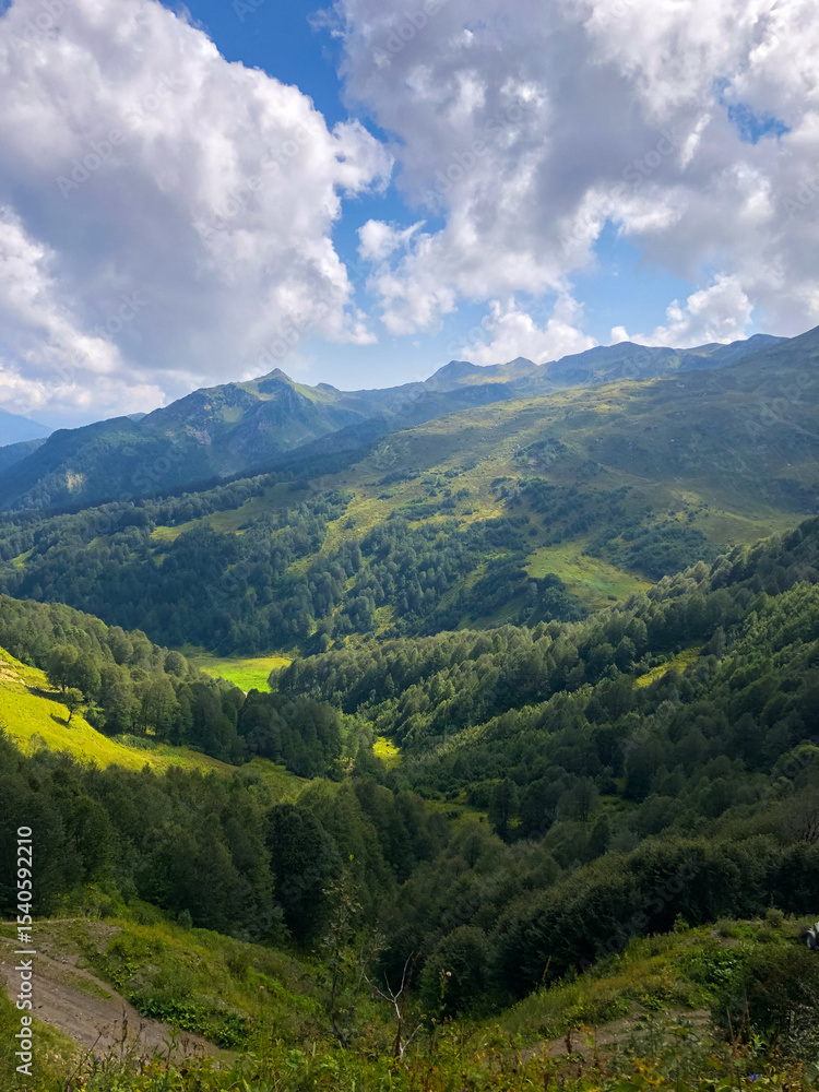 Fototapeta premium Clouds drifting over mountain peaks in Abkhazia, creating a dramatic and serene landscape