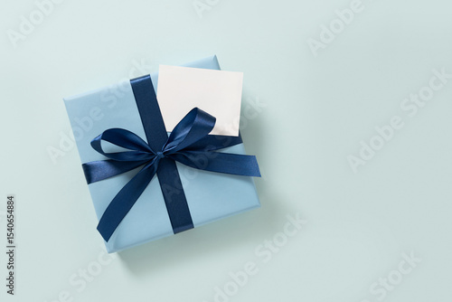 Blue gift box and empty white blank on plain pastel blue background. Flat lay. Happy Fathers Day. Greeting card. View from above. Copy space.
