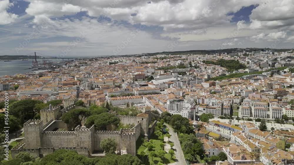 Drone facing west, flies backwards over Castelo de Sao Jorge in Lisbon, Portugal