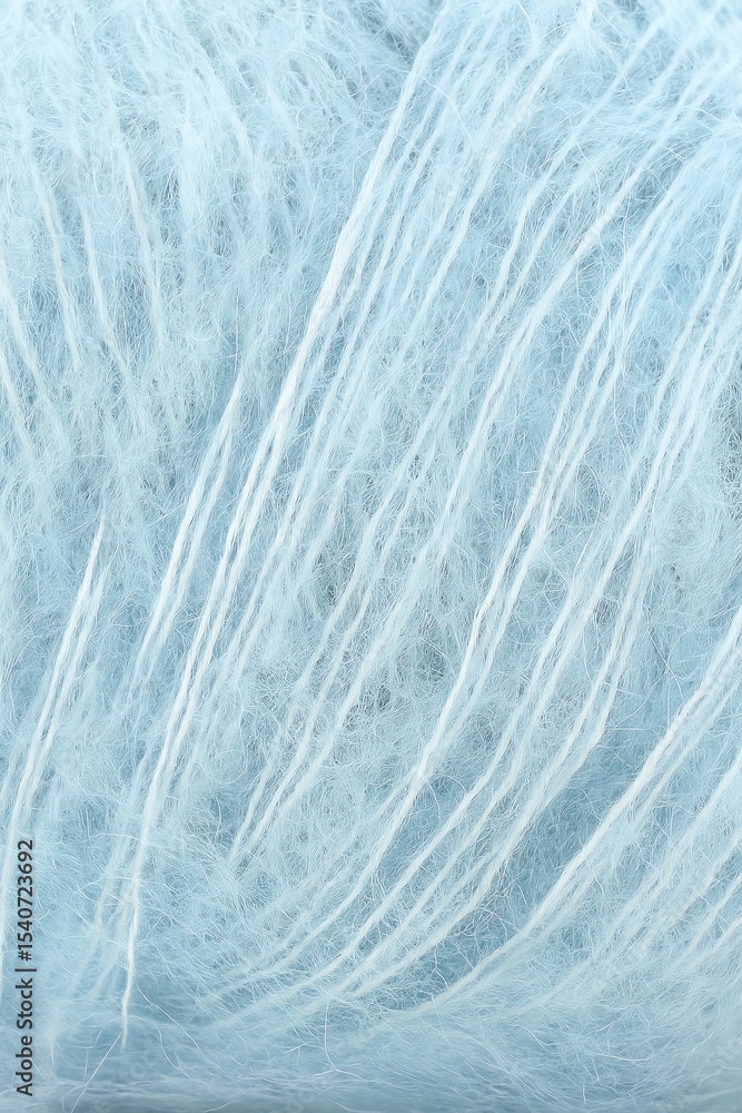 Obraz premium A macro close-up of soft light blue mohair yarn, showing delicate fuzzy fibers and long thin strands running through the textured bundle.