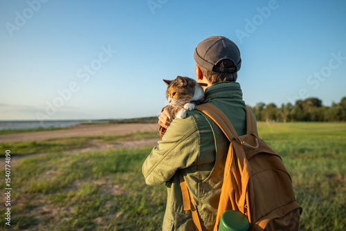 Foto Man walking with cat in arms outside on beach