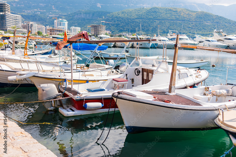 Obraz premium Small boats floating in marina with mountain backdrop. Coastal lifestyle, nautical tourism, and scenic summer destination.