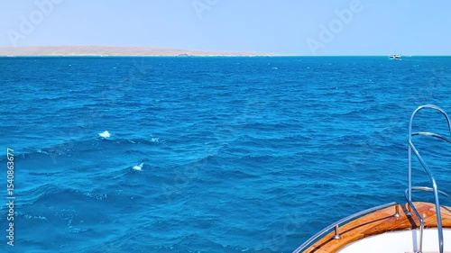Slow motion, View from bow of yacht on Saturated bright blue water of turquoise Red sea, front foredeck view, sunny clear day, summer mood for traveling and relaxing, serene ocean texture background