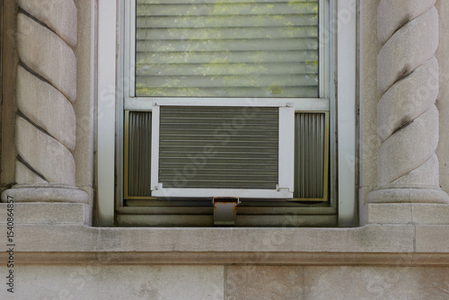 straight on, full, exterior view of air conditioning window unit extruding from the window sill with elegant, decorative concrete architectural details