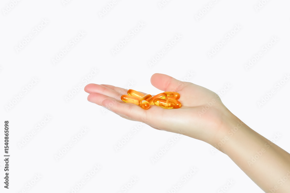 Hand holding a handful of yellow oil capsules isolated on white background Hand holding a handful of yellow oil capsules isolated on white background