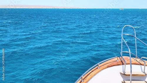 View from the bow of the yacht on Saturated bright blue water of warm turquoise Red sea, front foredeck view, sunny clear day, summer mood for traveling and relaxing, serene ocean texture background