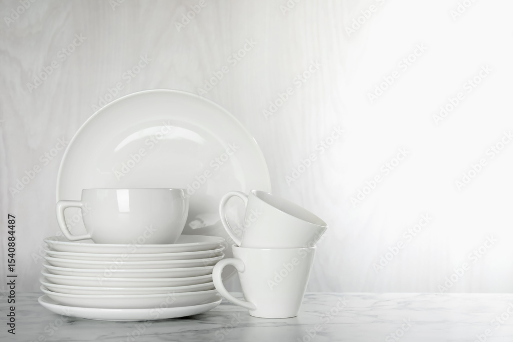 Fototapeta premium Different clean dishware on white marble table indoors, space for text