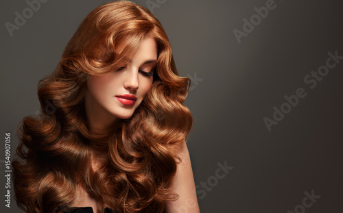 Red hair  girl with long  and   shiny wavy  hair .  Beautiful  model woman with curly hairstyle . Beauty and cosmetology