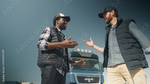 Low angle view of two smiling men shaking hands in sunlight in front of large truck. Celebrating partnership or closing deal. Exchanging respect and sealing agreement after discussion.