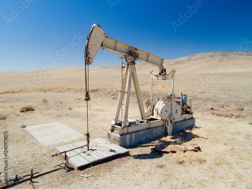 A Lufkin pumpjack extracts crude oil in a dry, arid landscape in Mckittrick, California, USA. The oil well pump is used to artificially lift liquid from a well when there isn't enough pressure.