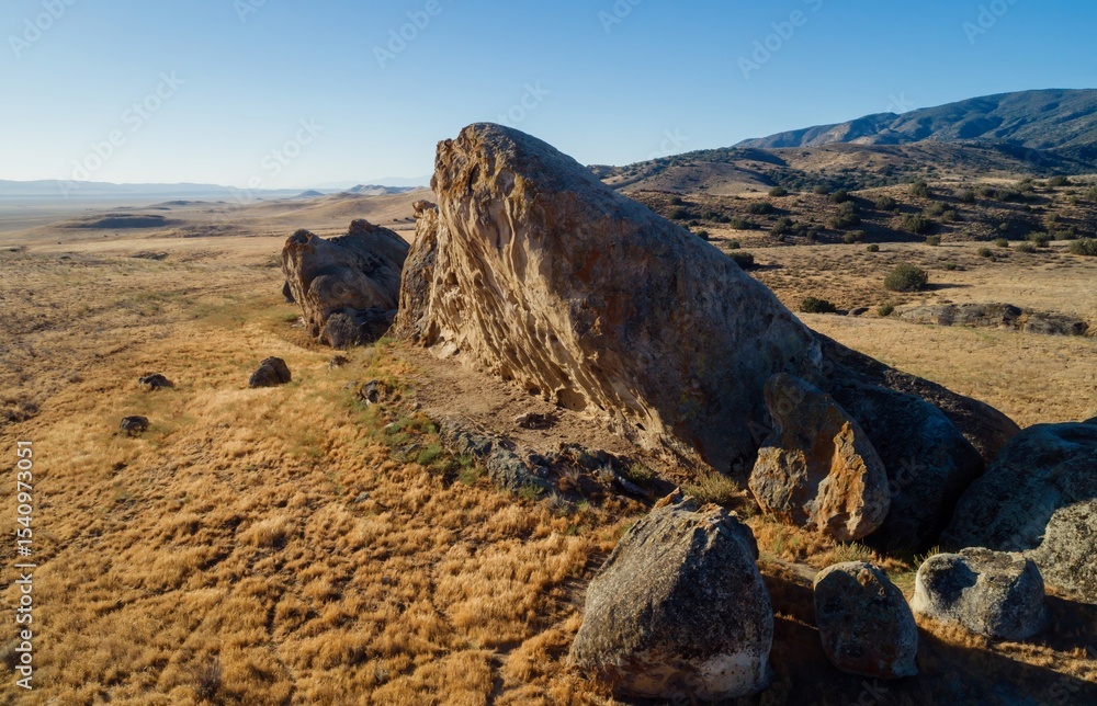 Obraz premium Scenic landscape of Carrizo Plain National Monument, California, USA. Large rock formations dot the golden, grassy hills under a clear blue sky.