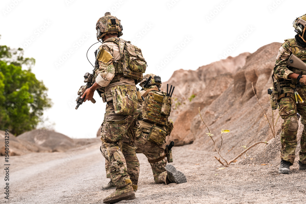 Fototapeta premium Special Forces Team Standing Together in Desert Mountain Terrain – Tactical Soldiers in Full Gear with Rifles, Communicating and Coordinating During a Military Operation or Training Mission