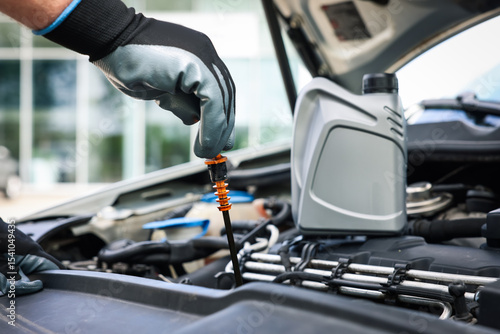 Fotografie Worker checking motor oil level in car with dipstick, closeup