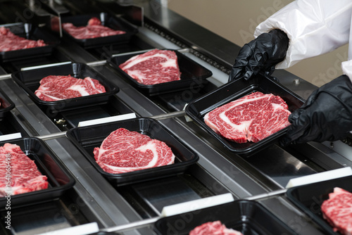 Steaks on a conveyor belt being packaged in a food processing plant