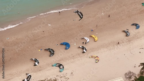 Aerial top view of kiteboarding gear and instructors offering kitesurfing lessons on sandy beach 