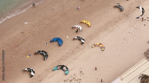Aerial top view of kiteboarding gear and instructors offering kitesurfing lessons on sandy beach 