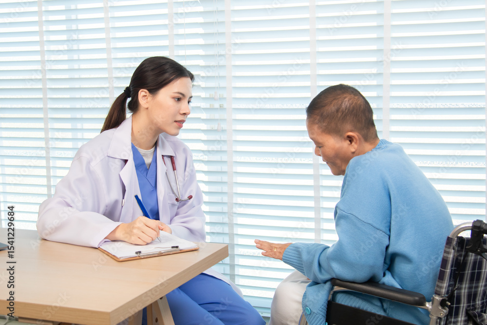 Female doctor consulting senior patient across table, pointing at laptop screen while discussing treatment plan in professional and friendly healthcare environment, illness, hospitality. Female doctor consulting senior patient across table, pointing at laptop screen while discussing treatment plan in professional and friendly healthcare environment, illness, hospitality.