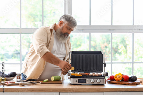 Mature man cooking tasty sa...