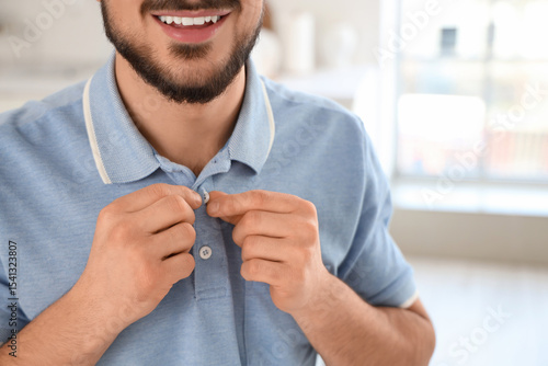 Young man buttoning up blue...