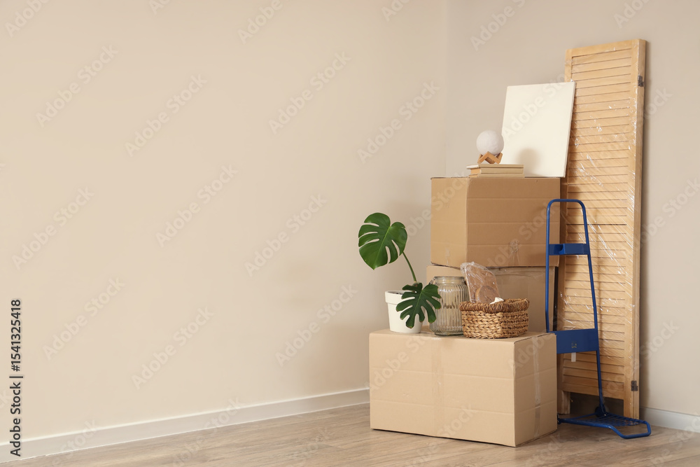 Fototapeta premium Cardboard boxes with wrapped folding screen and home decor in room on moving day