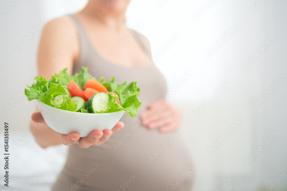 Expecting mother holding fresh vegetable salad while gently touching her belly. Healthy nutrition moment during pregnancy in cozy home setting. Expecting mother holding fresh vegetable salad while gently touching her belly. Healthy nutrition moment during pregnancy in cozy home setting.