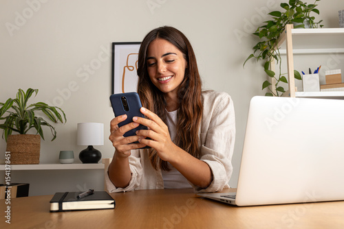 Young woman working using mobile phone working at home.