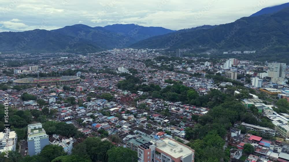 Drone shot over Ibague reveals sprawling urban landscape framed by lush mountains. Overcast sky provides soft lighting, creating a serene and expansive aerial panorama. Drone shot over Ibague reveals sprawling urban landscape framed by lush mountains. Overcast sky provides soft lighting, creating a serene and expansive aerial panorama.