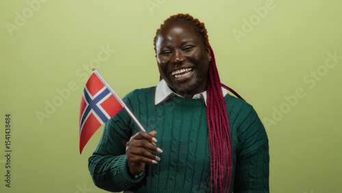 Fotografie Woman holding norwegian flag against yellow background in isolated joyful setting, showcasing cultural pride and heritage with vibrant expression and smiling face