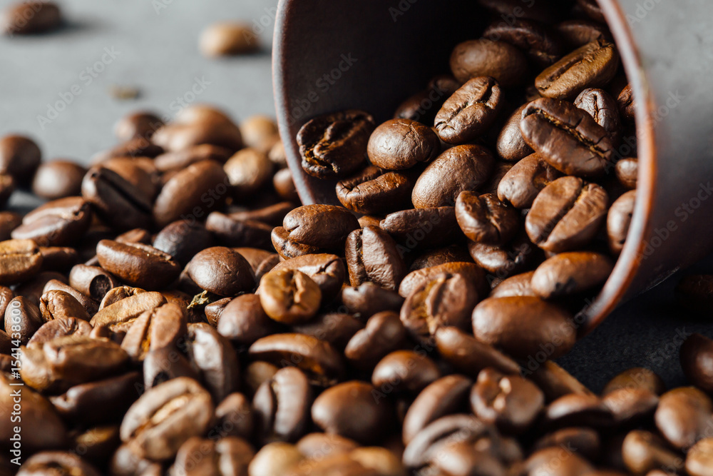 Fototapeta premium Freshly Roasted Coffee Beans Spilling from a Cup on Dark Surface