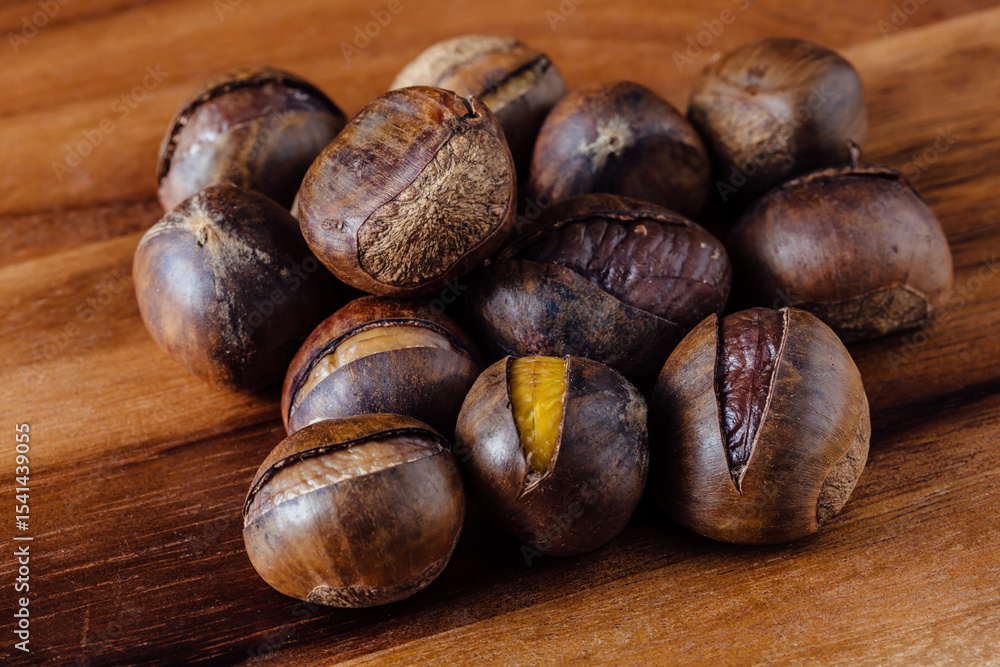 Obraz premium Freshly Roasted Chestnuts Piled on Wooden Table Surface