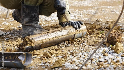 Man cutting and cleaning soil sample for laboratory analysis. Preparation of core material for geotechnical testing and scientific evaluatio