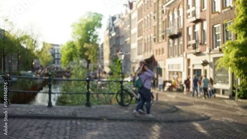 Wallpaper Mural Woman walking along defocused amsterdam canals with blurred background and warm sunlight casting over the bokeh cityscape, providing a serene urban scene. Torontodigital.ca