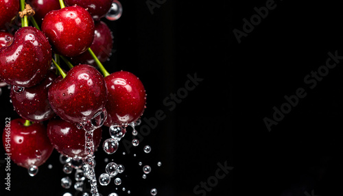 Fresh cherries with water droplets against dark background. Juicy red cherries splashing water droplets on black backdrop. Copy space for text or logo.  Perfect image for food blogs, recipe websites
