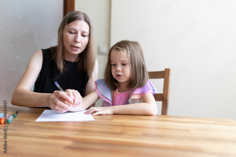 Teacher helping young girl writing on paper at desk Teacher helping young girl writing on paper at desk