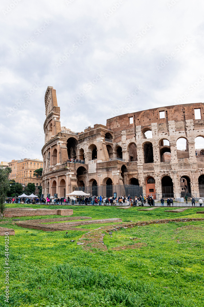 Fototapeta premium The iconic Roman Colosseum, a symbol of ancient Rome, stands majestically as tourists gather to admire its grandeur
