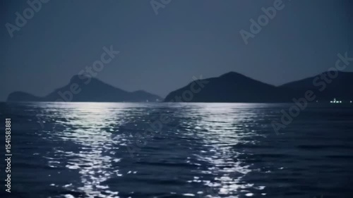 Moonlight reflecting on a still sea, silhouettes of mountains