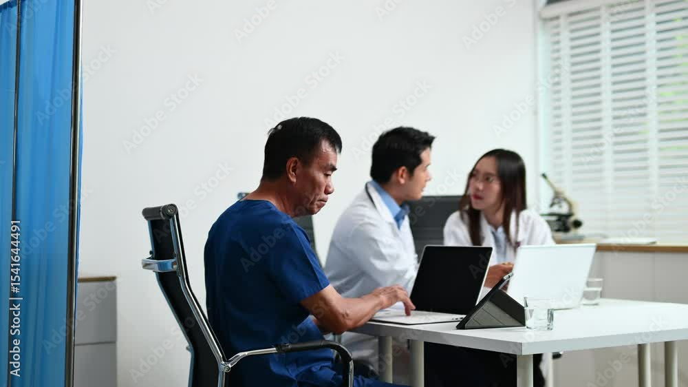 Doctor reviews a medical form with senior patient, assisted by a healthcare team using laptops in a modern clinic. Doctor reviews a medical form with senior patient, assisted by a healthcare team using laptops in a modern clinic.