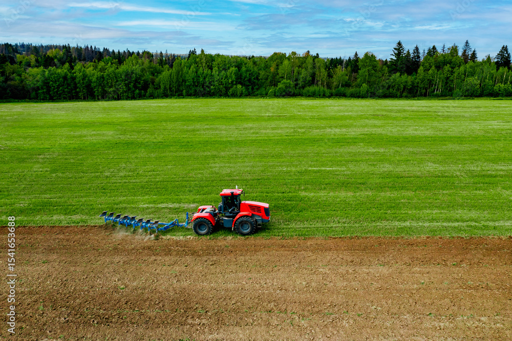 Aerial View of Red Tractor Plowing Field. Tractor and field. Agricultural machinery working on farming field Aerial View of Red Tractor Plowing Field. Tractor and field. Agricultural machinery working on farming field